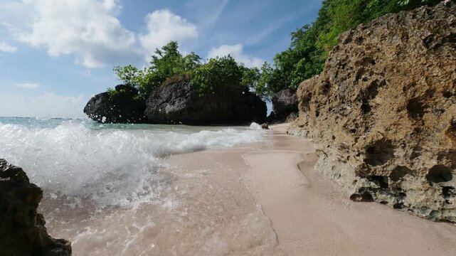 Padang Padang beach in Uluwatu, Bali. Near Pecatu.  (Pantai Labuan Sait) Slow motion of the waves crashing into the limestone rocks and white sand. Indonesian Summer. The tide is coming in. Turquoise 