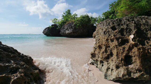 Padang Padang beach in Uluwatu, Bali. Near Pecatu.  (Pantai Labuan Sait) Slow motion of the waves crashing into the limestone rocks and white sand. Indonesian Summer. The tide is coming in. Turquoise 