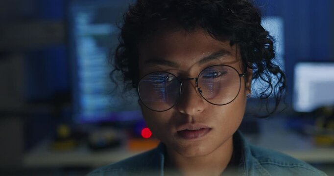 Close-up Black female programmer with code reflection in glasses working late in home office at night. Cybersecurity, AI algorithm, Network security, software developer, serious face, burnout concept.