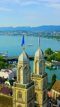 Vertical video. Zurich, Switzerland. Grossmunster Church with its twin neo-Gothic towers, aerial panoramic view over the Limmat River and Lake Zurich under clear summer skies. Drone footage, Point of