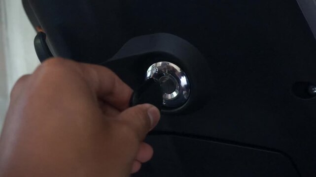 A close-up of a hand turning on the ignition of an electric motorcycle, highlighting the concept of a transportation startup.
