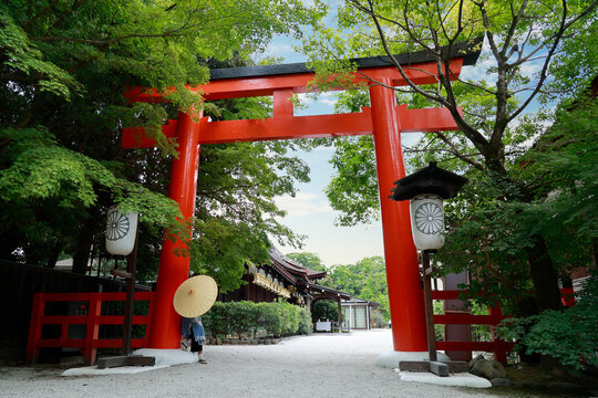 Low angle view of red torii gate with woman in kimono and wagasa umbrella at Kamigamo shrine, Kyoto, Japan