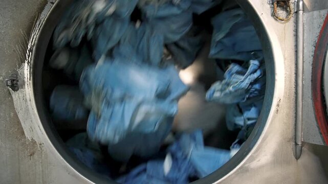 Wet Blue Jeans Spinning and Tumbling inside Large Metal Industrial Washing Machine at Denim Factory Textile Manufacturing Plant 4k
