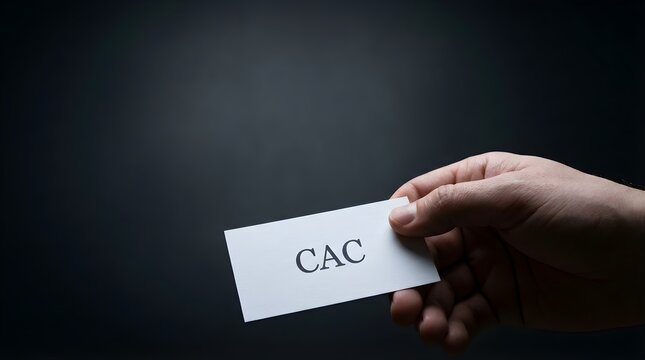 Hand holding white business card with cac text label against a dark moody background for corporate finance