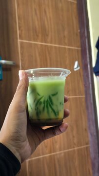 hand holding a cup of cendol iced