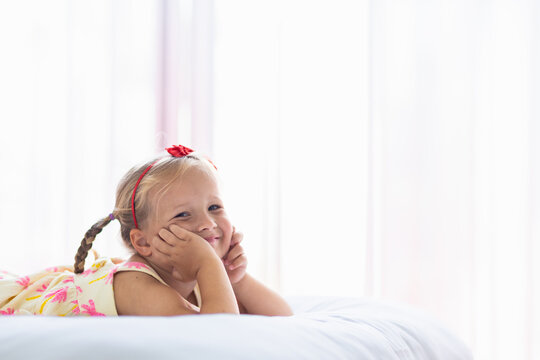 Smiling young girl with braided hair lying on a bed