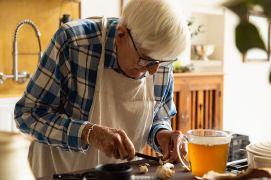 elderly man in light filled kitchen preparing a pot roast 