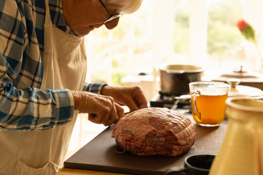 elderly man in light filled kitchen preparing a pot roast 