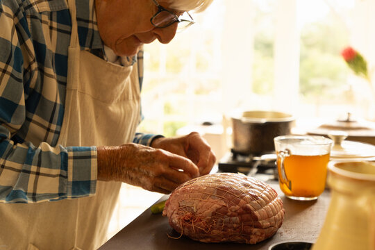 elderly man in light filled kitchen preparing a pot roast 