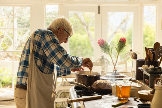 elderly man in light filled kitchen preparing a pot roast 
