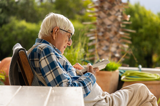 elderly man reading paperback book outdoors