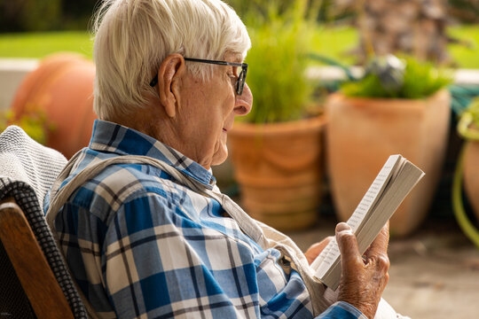 elderly man reading paperback book outdoors