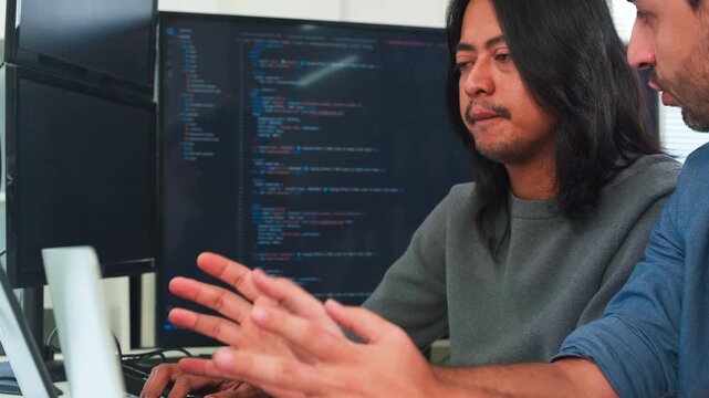 Focused developer using tablet in modern office, professional software engineer working on digital project with coworker in background