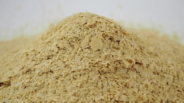 Slow Motion Pouring of Nutritional Yeast Flakes on White Background