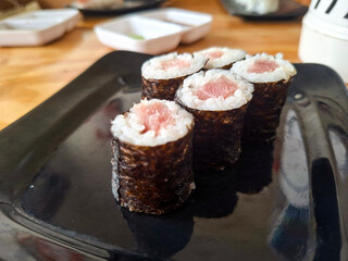 A close-up, eye-level perspective focusing on the texture and height of the tuna maki sushi rolls © awgraphoto