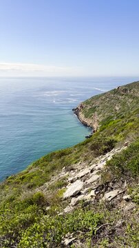 Mom with children hike along scenic coastal trail on Robberg peninsula. Vertical
