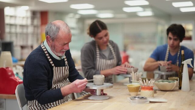Mature man at table molds cup from wet clay in a pottery workshop. High quality 4k footage