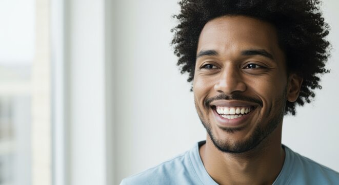 Smiling young man with curly hair looking away indoors for dental care advertising, positive lifestyle imagery and wellness campaign with copy space on white background