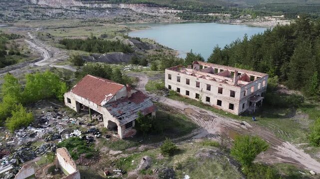 Aerial view of abandoned ruined buildings and garbage dump near a quarry lake