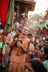 Fototapeta premium Man in orange robe playing brass cymbals during a crowded religious festival for documentary storytelling, cultural travel promotion and spiritual editorial content