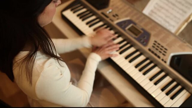 Woman playing music synthesizer. Musician practicing keyboard for tutorial lesson. Concept of remote digital music education, course and learning melody at home