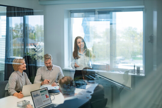 Business team discussing together business plans in office, view from glass wall