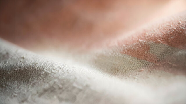 Woven linen texture displaying a gentle gradient from cream to soft blush under warm light