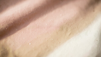 Fototapeta premium Golden sunlight illuminating the subtle blush to creamy beige gradient of woven fabric