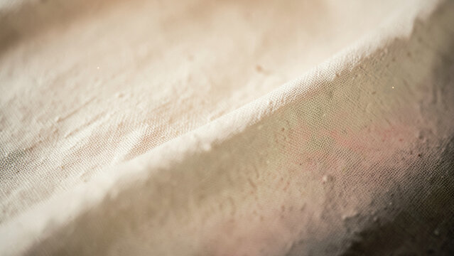 Close up perspective of woven fiber showing subtle beige to blush gradient under warm light
