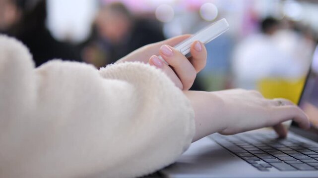 Person multitasking on laptop and phone. Hands show focus and modern work habits. Ideal for digital work, remote job, or tech lifestyle themes