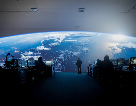 aerospace engineers monitoring orbital debris threats in a futuristic satellite tracking and communication control room.