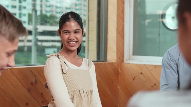Young student smiling while listening other student in meeting or group discussion. Cute teenager talking about her experience and sharing to friends in mixed races. Creative education. Edification