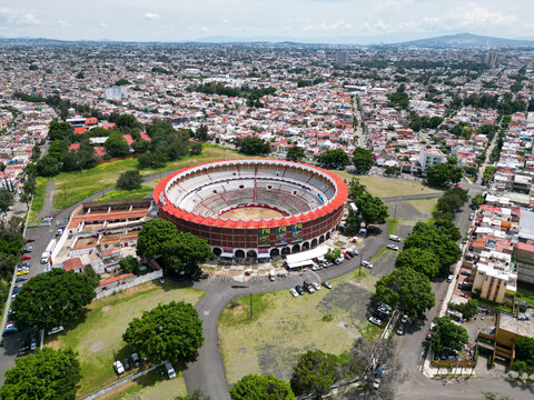 Guadalajara, Mexico - September 7 2025: Aerial view of Plaza de Toros Nuevo Progreso in Guadalajara, featuring its circular design and red roof amidst urban and green areas under a bright sky.