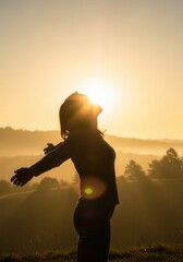 Fototapeta premium Silhouette of a Woman with Outstretched Arms at Sunrise, Concept of Freedom, Hope and Mindfulness in Nature