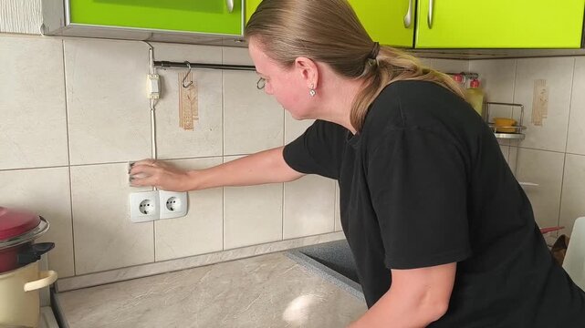 A woman cleans a tile apron in the kitchen with a napkin, a household scene of cleaning, caring for the work area and maintaining cleanliness.
