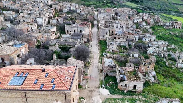 Aerial panorama of Poggioreale Vecchia, the abandoned Sicilian village with ruined stone buildings amid green hills.