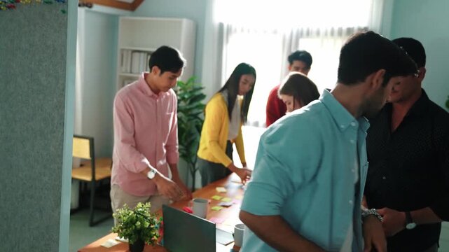 Top down aerial view of smart team choosing idea from sticky notes and stick at whiteboard. Multicultural people planning strategy start up project while put it on board at meeting room. Convocation.
