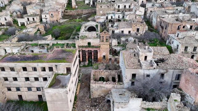 Aerial panorama of Poggioreale Vecchia, the abandoned Sicilian village with ruined stone buildings amid green hills.