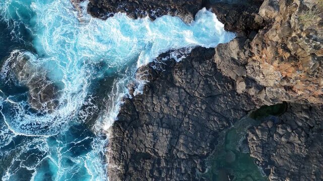 Waves hitting rocks on the beachside view from top 