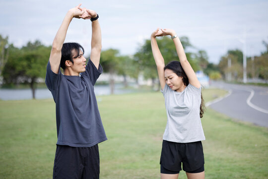 Young Asian Couple Stretching Together Outdoors Before Workout