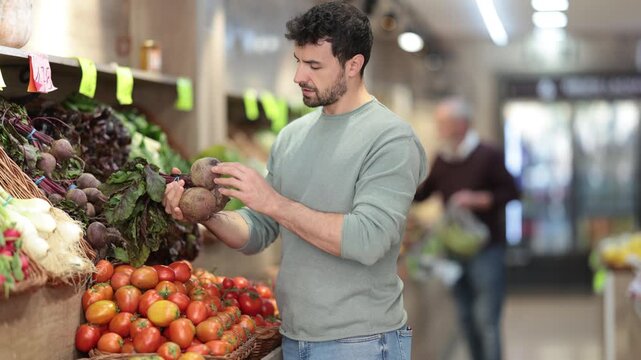 Adult man buyer choosing fresh beets in vegetable shop