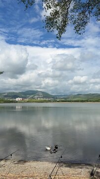 Wild ducks swim in the calm water of Lisi Lake in Tbilisi, Georgia, with fishing rods set up on the shore. Great footage for outdoor recreation, fishing hobby, summer travel, and nature themes.