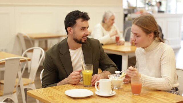 Father and teenage daughter sitting at table in cafe. Light snack or coffee break at restaurant, family getaway or pastime. Family time, Sunday lunch at chain cafe in capitals pedestrian tourist area.
