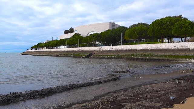 Champalimaud Foundation Building and Tagus River Promenade in Lisbon, Portugal with Calm Waves Lapping on the Shore