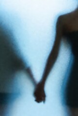 Fototapeta premium Romantic Silhouette of Couple Holding Hands Behind Frosted Glass Background with Soft Blue Light and Grainy Texture for Mental Health Relationship Support and Loneliness Concept