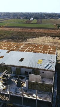 Fly around a construction of warehouse with a crane surrounded with countryside