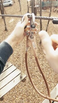 Climbing park attaching safety belts from wire to wire person POV