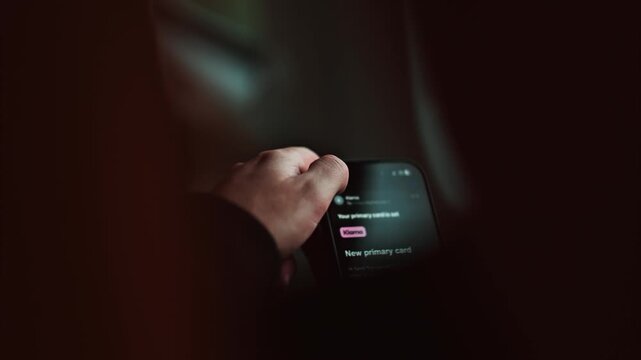 Hand holding smartphone at night screen glowing with notifications and payment app interface.