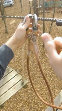 Climbing park attaching safety belts from wire to wire person POV
