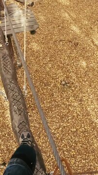Climbing course high above ground in adventure park person POV 